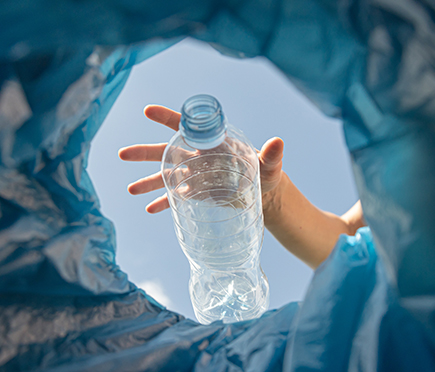 a plastic water bottle being thrown into a bin
